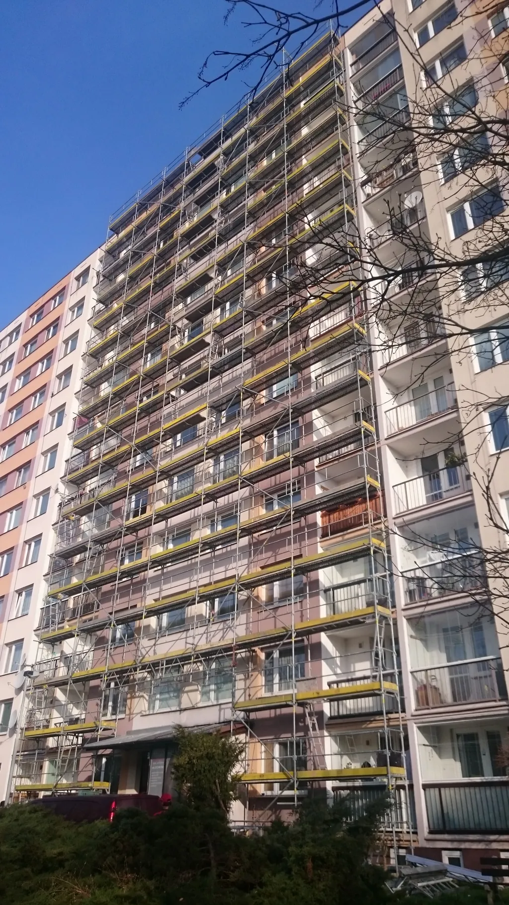 Výškový panelový dům s lešením po celé výšce fasády